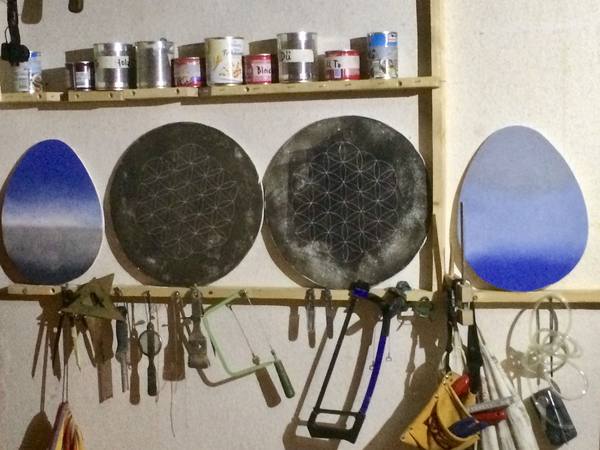 Mehrere runde Scheiben in der Werkstatt, daneben Farbtöpfe.